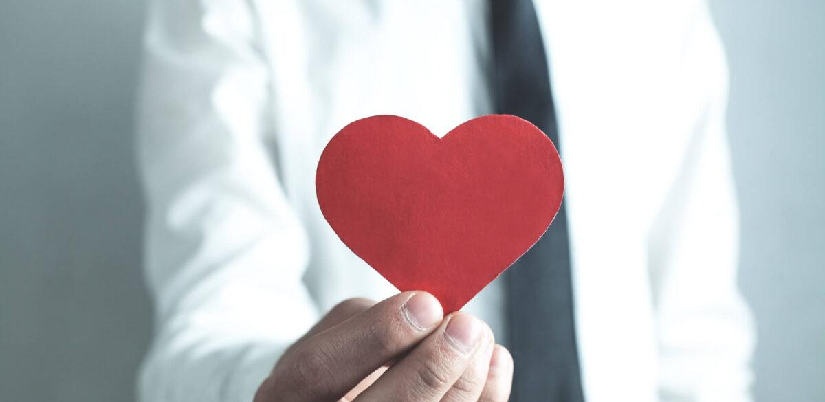 A corporate employee holds a paper heart, representing CSR.