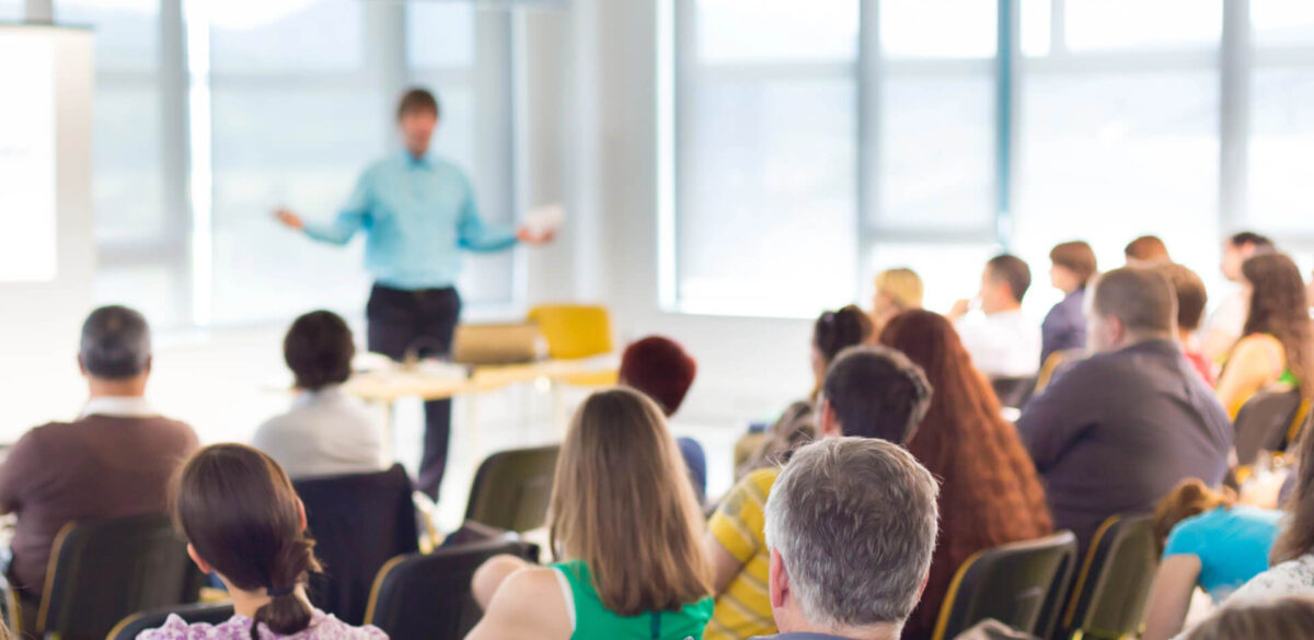 Group of people listening to a speaker in an auditorium.