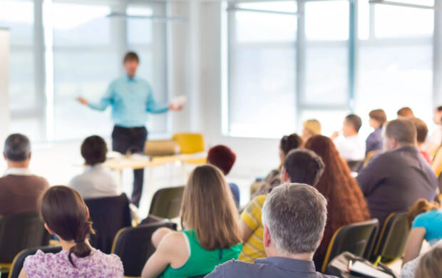 Group of people listening to a speaker in an auditorium.